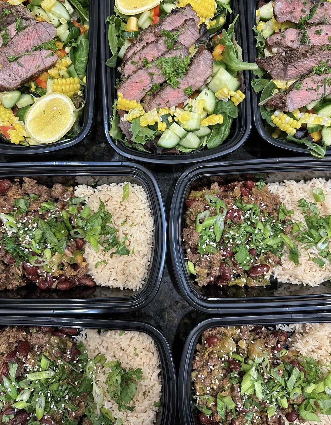 Rows of packed meal-prep containers with steak salad and rice bowls